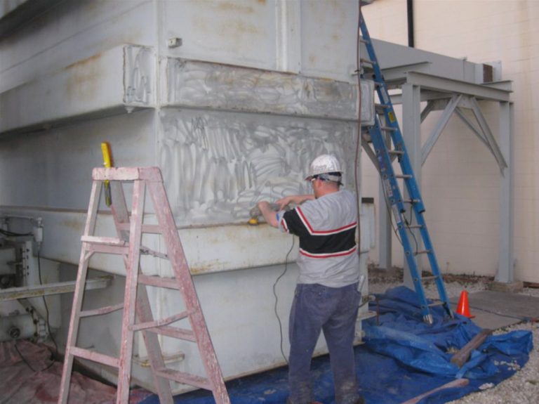 man cleaning and preparing an electrical transformer to be painted