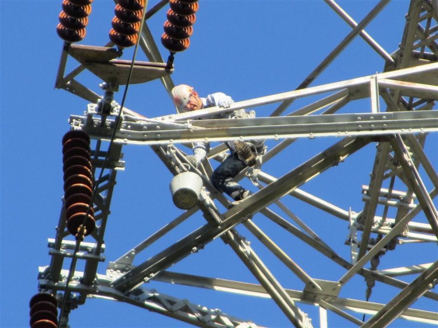 man painting electrical transmission tower