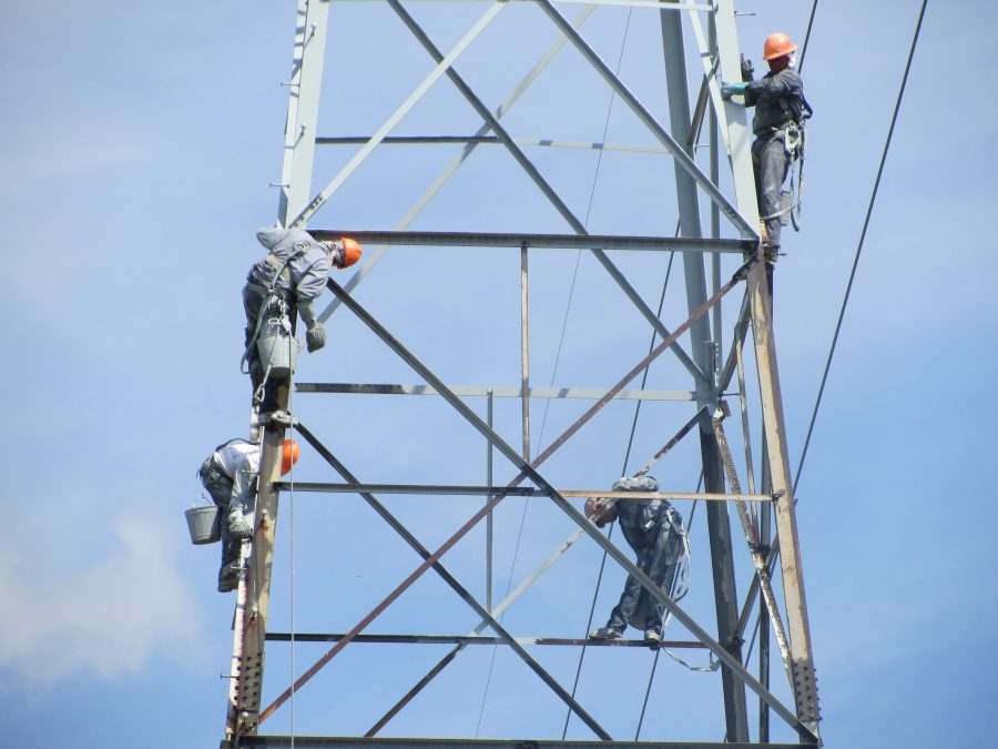 a group of men painting an electric tower