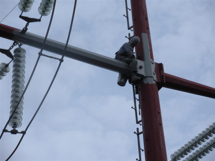 a man painting an electrical transmission pole