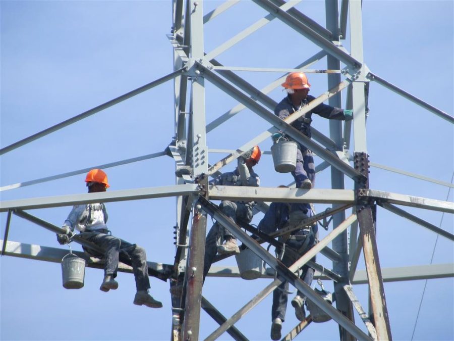 a group of men painting a transmission tower